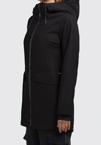 Vandtæt sort parka-jakke med hætte, frontlynlås og to store frontlommer. Har en glat tekstur og justerbare snore.