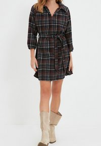 Kostkované šaty v námořnické modři, burgundské a bílé barvě s límečkem, dlouhými rukávy a odpovídajícím páskem. Měkká tkanina s uvolněným střihem.