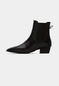 Bota ankle preta com um padrão de crocodilo texturizado, bico fino e pequeno salto bloco. Apresenta painéis laterais elásticos e uma alça de puxar.