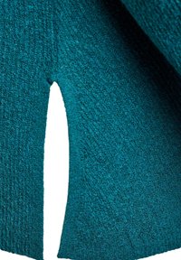 Teal fabric feature with a textured surface and a cut-out detail, showcasing a soft, woven appearance and a slightly irregular edge.