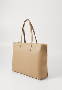 Sac cabas synthétique beige avec deux longues anses, forme rectangulaire, texture lisse et lignes épurées ; sans quincaillerie ni motifs visibles.