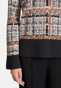 Knit sweater featuring a multi-color geometric pattern with shades of gray, black, and rust. Black cuffs and hem provide contrast.