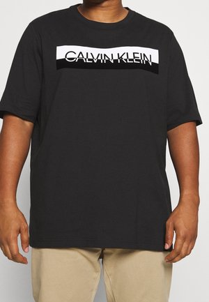 Černé bavlněné tričko s bílým a černým logem Calvin Klein přes hrudník. Krátké rukávy a volný střih.