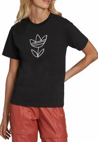 T-shirt nera in cotone con un design grafico floreale bianco centrato sul petto. Maniche corte e vestibilità classica.