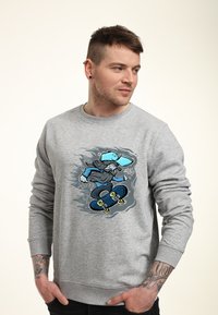 Grå huvtröja med en färgstark grafik av en skateboardåkare i blått och svart, med ribbad mudd och rundad krage.