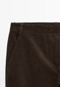 Donkerbruine corduroy broek met verticale ribbels, voorzien van een tailleband, een voorzak en keurig gestikte randen.