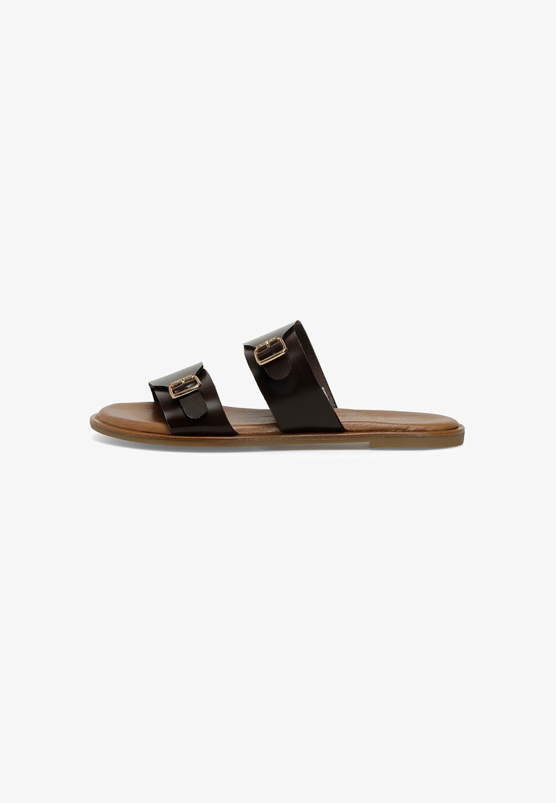 Brown leather sandals with two wide straps, each featuring a metallic buckle. Flat sole with a smooth brown base. Simple and minimalist design.
