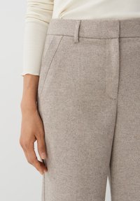 Lichtbruine textuurbroek met een getailleerde pasvorm, voorzien van voorplooien en een gladde tailleband, gecombineerd met een crème lange mouwen top.