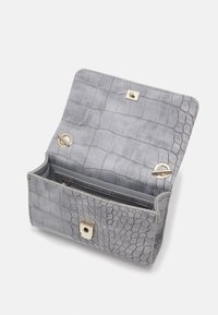 Grå handväska med krokodilsmönster, öppen för att visa det inre facket med dragkedja och detaljer i guldnyans på vit bakgrund.