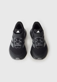 Mustad spordijalatsid võrguga pealisse, hallide detailide ja kummist tallaga. Omavad lamedaid paelu ja polsterdatud ääre mugavuse tagamiseks.