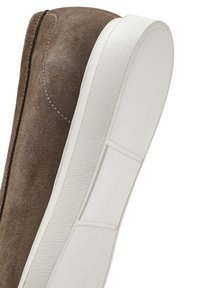 Sneaker in camoscio marrone con suola in gomma bianca, texture liscia e dettagli di cucitura in rilievo lungo il bordo superiore.