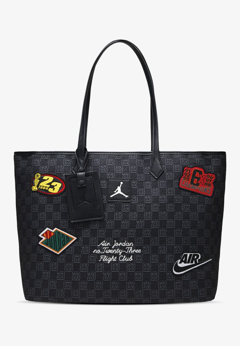 Zwarte draagtas met een gegolfde textuur. Het bevat verschillende patches en ontwerpen, zoals logo's, tekst en kleuraccenten.