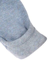 Blå stickad tröjsleeve med en mjuk filtmanchett. Texturen är slät och tyget visar en blandning av ljusblå och mörkblå nyanser.