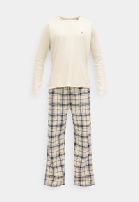 Krém színű hosszú ujjú felső bordázott textúrával és kis logóval; kockás pizsamanadrág krém, fekete és bézs színekben. Laza szabás.