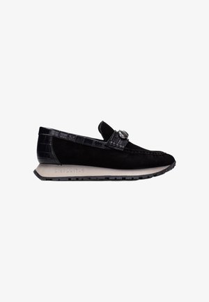 Zapato de charol negro sin cordones con una correa de cuero texturizada con patrón de cocodrilo y acentos. Cuenta con una suela de goma y la marca grabada "Hispanitas".