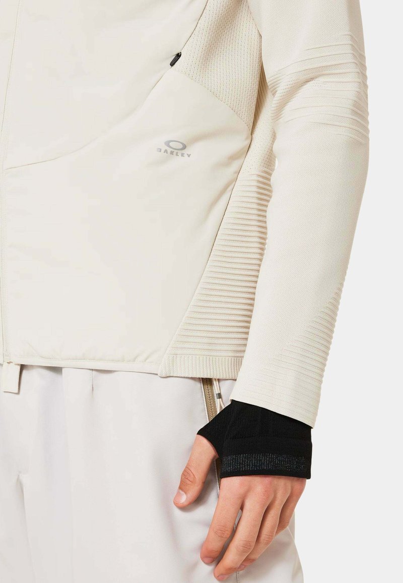 Helle, strukturierte Zip-Jacke mit einer taillierten Passform; verfügt über eine Tasche und schwarze Strickbündchen. Logo auf der Brust.