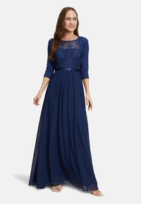 Robe de soirée bleu marine à manches trois-quarts, corsage en dentelle, jupe fluide et ceinture en satin ; texture lisse et design long jusqu'au sol.