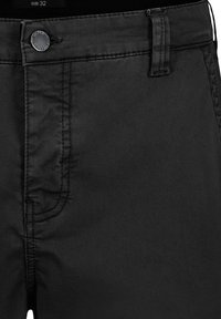 Black pants in a smooth fabric with a straight cut. Features a button closure and contrasting stitching along the seams. Size label visible.