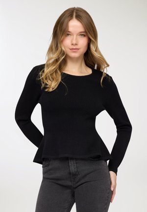 Maglione nero a costine con corpino aderente e orlo a peplo svasato, caratterizzato da maniche lunghe e scollo rotondo. Abbinato a jeans scuri.