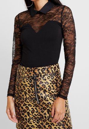 Black bodysuit with sheer lace long sleeves, collared neck, and a fitted design; paired with a leopard print zip skirt in gold and brown tones.