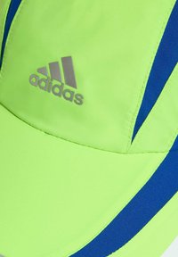 Gorra verde neón con acentos azules, con un logo plateado de Adidas. Fabricada con tela suave, diseñada con una visera curva y costuras cosidas.
