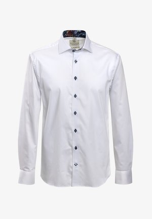Chemise blanche à manches longues en tissu lisse, avec un col à motif sombre et des boutons navy à l'avant.