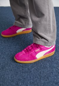 Baskets en daim rose et maille avec des accents blancs et une semelle en caoutchouc naturel. Elles présentent des lacets et une étiquette logo sur le côté.