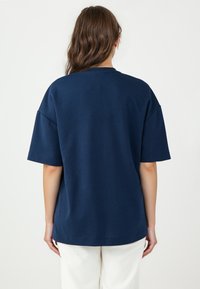 Marineblaues, übergroßes T-Shirt aus weichem Baumwollmix. Mit kurzen Ärmeln, Rundhalsausschnitt und geradem Saum auf Taillenhöhe.