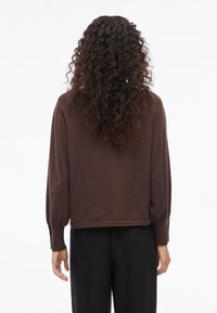 Rudas megztinis su ilgomis pūstomis rankovėmis, pagamintas iš minkštos medžiagos. Turi trumpą hemą ir laisvą kirpimą.