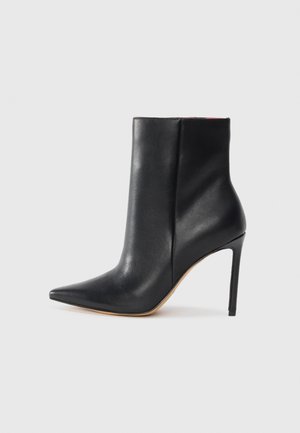 Zwarte leren enkelboot met een spitse neus, hoge stilettohak en een gladde textuur. Heeft een minimalistisch ontwerp zonder zichtbare hardware.