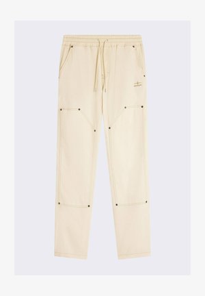 Un pantalon de jogging crème avec une taille élastique, un cordon de serrage, deux grandes poches latérales et des accentuations de couture contrastées.