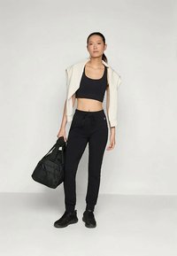 Melna sporta topa bez piedurknēm, melni sporta bikses ar saites, krēma krāsas ārējais slānis uz pleciem, un melna soma. Melni apavi piešķir akcentu izskatam.