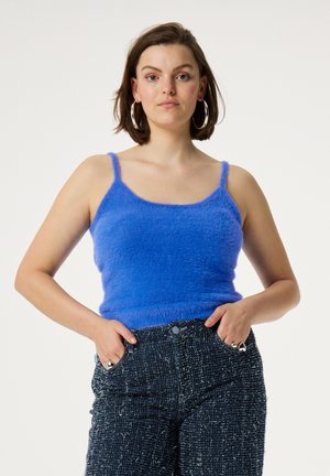 Blauwe fluffy tanktop met dunne bandjes, gecombineerd met donkere, gestructureerde denim broek. Gladde textuur en levendige kleur zijn opvallende kenmerken.