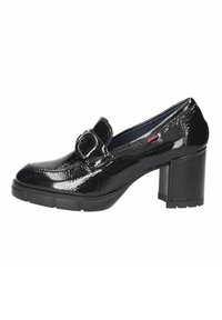 Zapato de charol negro de tacón alto con punta redondeada, que presenta un gran detalle de hebilla circular en el empeine y un tacón grueso y texturizado.