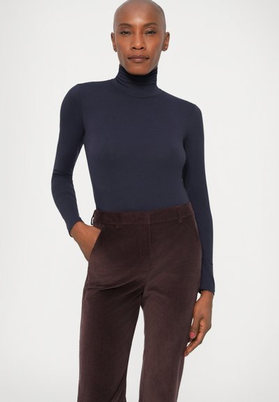 Mere turtleneck navy tooni, mis on valmistatud elastsetest materjalidest, koos tumeda burgundi värvi kootud pükste paariga, millel on ees taskud ja sirge sääremood.