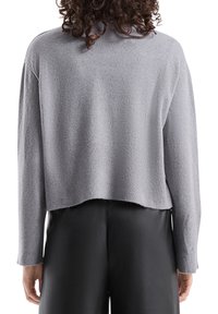 Szary krótki sweter o miękkiej fakturze, z długimi rękawami i prążkowanym brzegiem. Charakteryzuje się luźnym krojem, pokazany od tyłu.