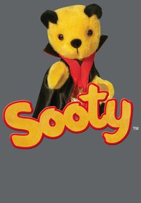 Sødt stofbjørne i gul pels, iført en sort kappe og rød krave. Bemærkelsesværdige træk inkluderer runde ører og en sort næse. "Sooty" tekst nedenfor.
