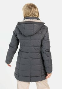 Grijze pufferjas met een capuchon, voorzien van een geborduurd ontwerp en een zachte voering. De jas heeft lange mouwen en een licht gebogen zoom.