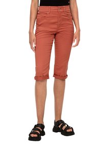 Pantaloni capri color ruggine in denim, con una vestibilità slim, orli arrotolati e tasche frontali. Abbinati a sandali sportivi neri.