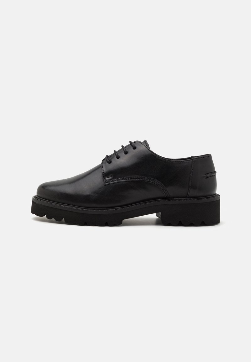 Chaussure à lacets en cuir noir avec semelle épaisse et crantée et talon bas et épais, vue de côté sur fond uni.