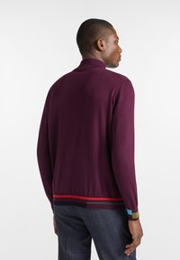 Bordeauxfarbenes Strickpullover mit hohem Kragen. Verfügt über einen gerippten Saum mit roten, schwarzen und blauen Streifen. Glatte Textur und figurbetontes Design.