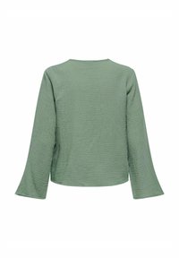 Top largo de mangas largas en verde, texturizado, con cuello redondo y mangas anchas, que presenta una superficie de tela arrugada y una silueta relajada.