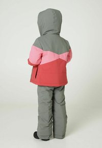 Veste de ski en blocs de couleurs avec une capuche grise, des sections roses et rouges, associée à un pantalon de neige gris et des bottes noires. Tissu lisse et isolé.