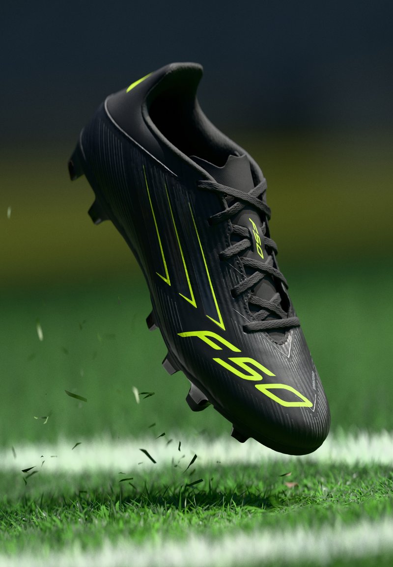 Black soccer cleat with textured surface, bright yellow accents, lace-up design, and a lightweight construction, hovering above grass.