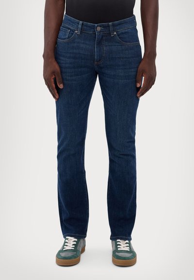 Dark blue denim jeans with a straight leg cut, featuring front pockets and a button closure. Worn with gray and green sneakers.
