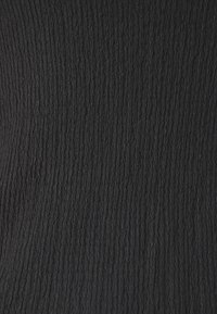 Tissu noir texturé avec des motifs en côtes verticales, créant une apparence de surface tactile. Convient pour les vêtements ou le rembourrage.
