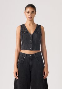 Veste courte en denim noir avec décolleté en V, boutons avant et deux poches poitrine, assortie à un jean noir à taille haute et jambes larges.