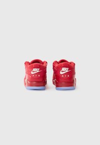 Røde Nike Air sneakers med en glat læderoverdel, polstret krave og en lyseblå gummisål. Har fremtrædende logoer på bagsiden.