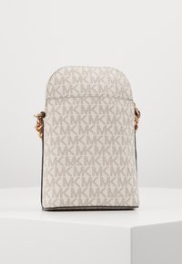 Beige kangaskäsilaukku, jossa on toistuva "MK"-logokuvio, pyöristetty yläosa ja kullanväriset metalliosat. Laukussa on vetoketjullinen suljenta.