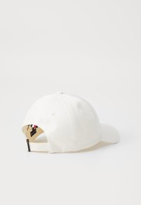 Cappellino da baseball bianco con visiera curva, dotato di fori di ventilazione, cinturino regolabile e un piccolo dettaglio multicolore sul retro.
